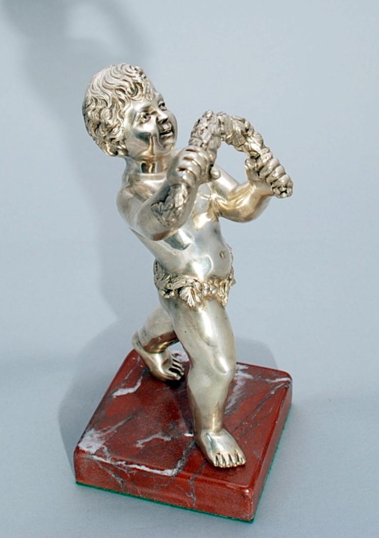 Continental solid silver sculpture of large cherub mounted on marble base measuring 11 1/2 inches in height on its base and holding a large garland of flowers. The figure is of very high quality and is very detailed and its height is 9 3/4''. The