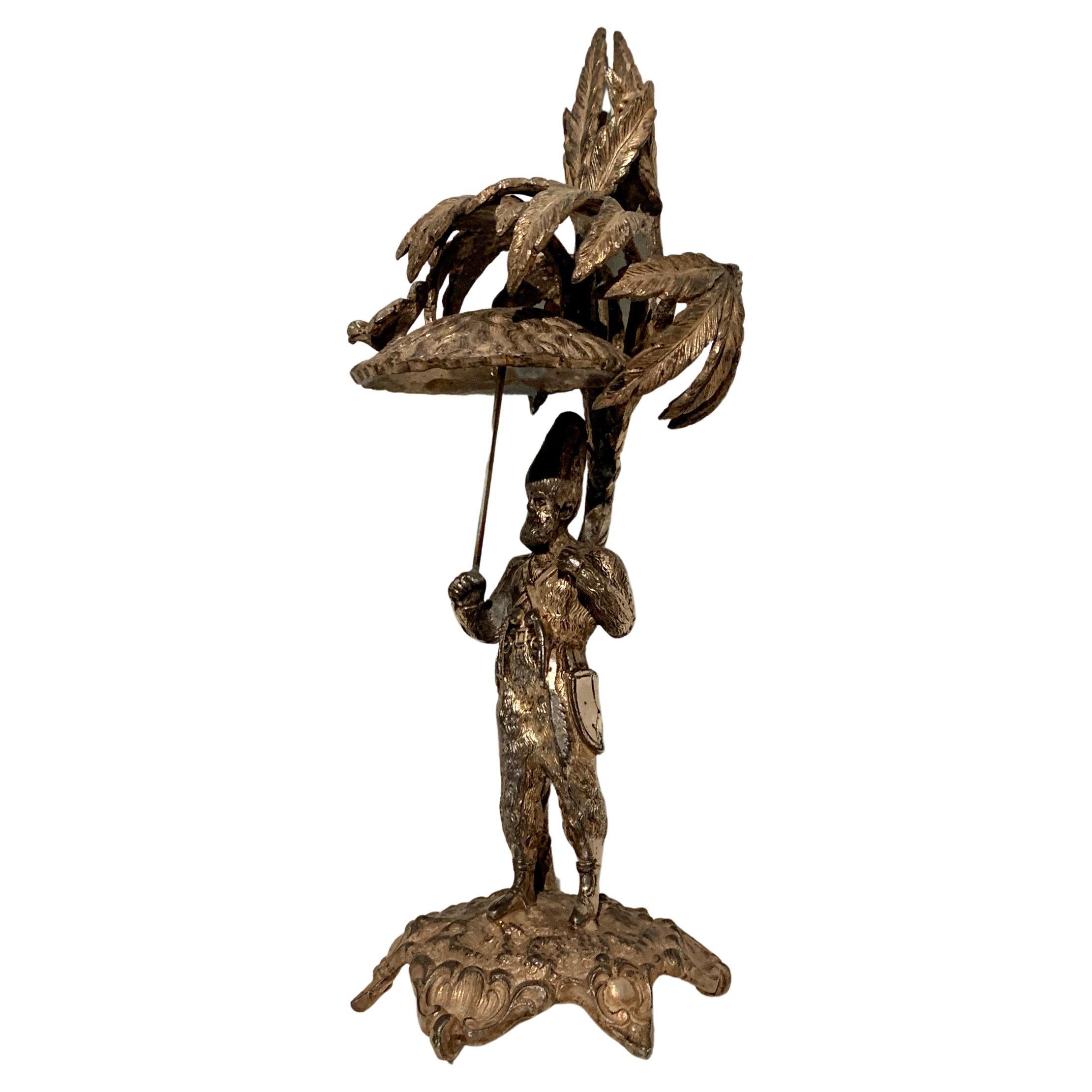 Escultura de plata de un hombre que sostiene un paraguas con un pájaro