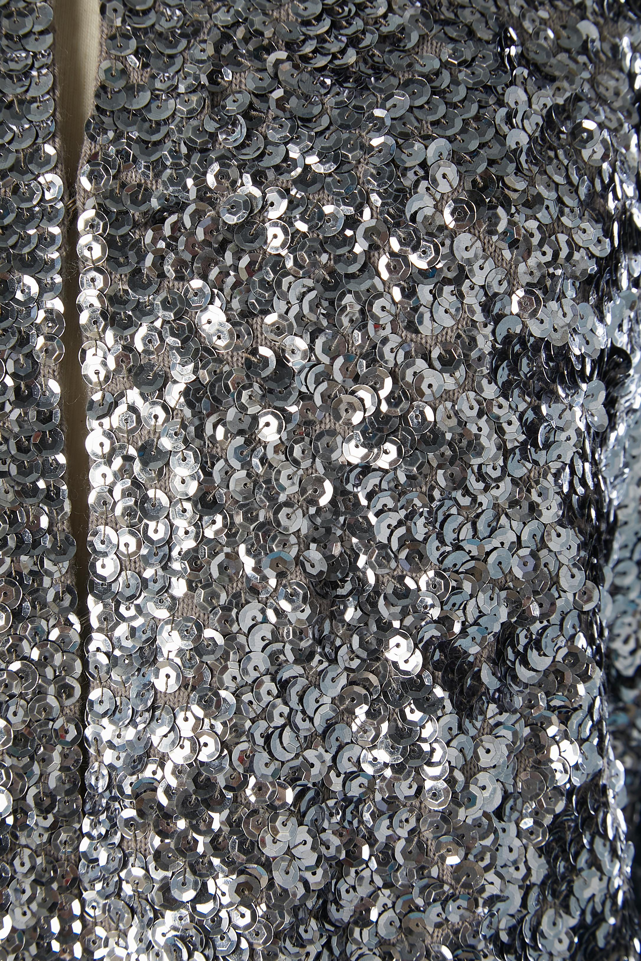 Silver sequin edge to edge evening jacket on a grey knit base. Lining probably in acetate or rayon. Split on both side, lenght: 8cm
Hook&eye closure on the middle front. 
SIZE 38 (Fr) M 