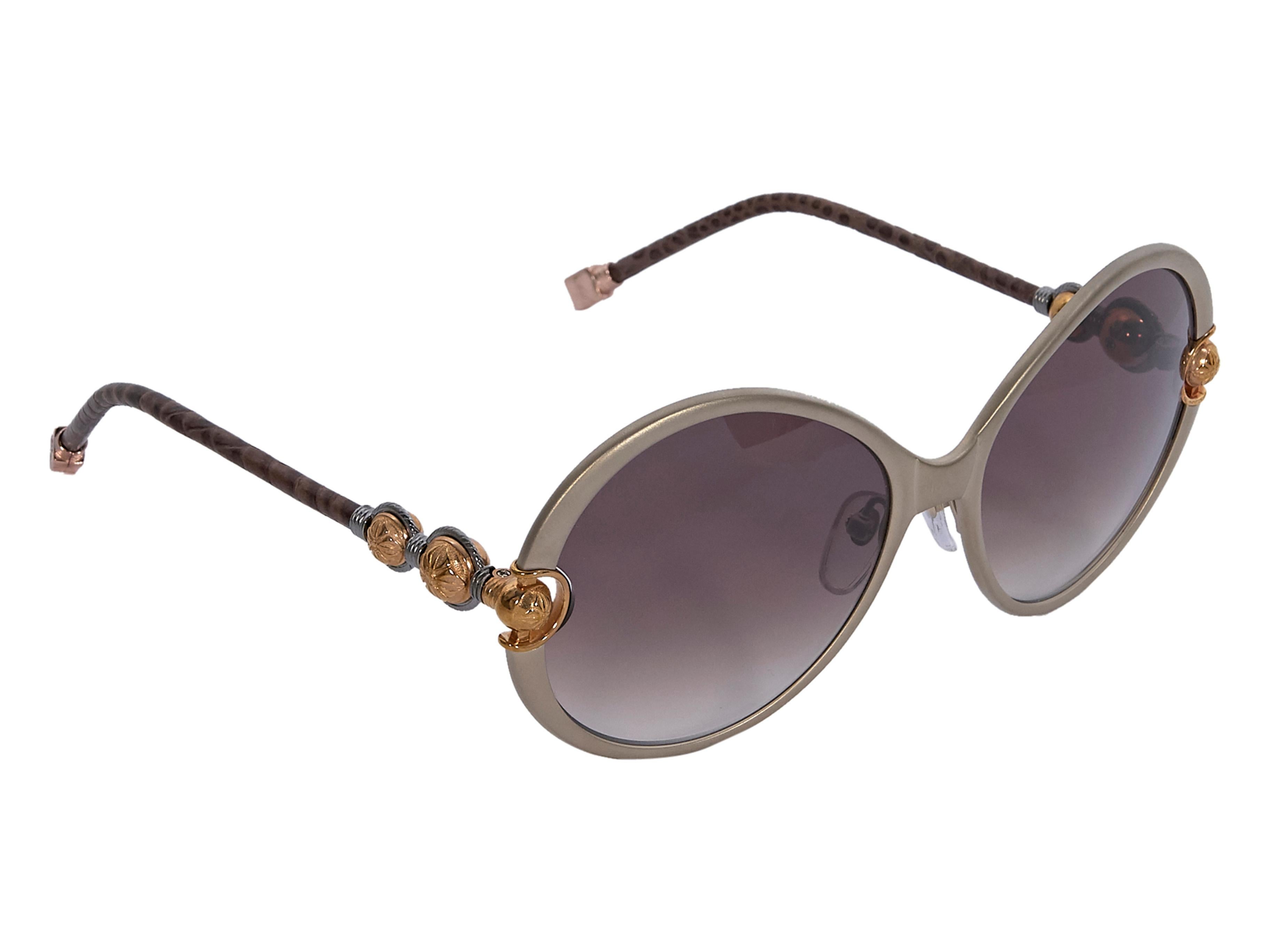 Product details:  Silver round Divinity sunglasses by Shamballa. Snakeskin leather wrapped stems. Cushioned nose pads. Embossed bronze-tone accents at front and stems. Bronze-tone hardware. Wear yours with an animal-printed swimsuit.  6