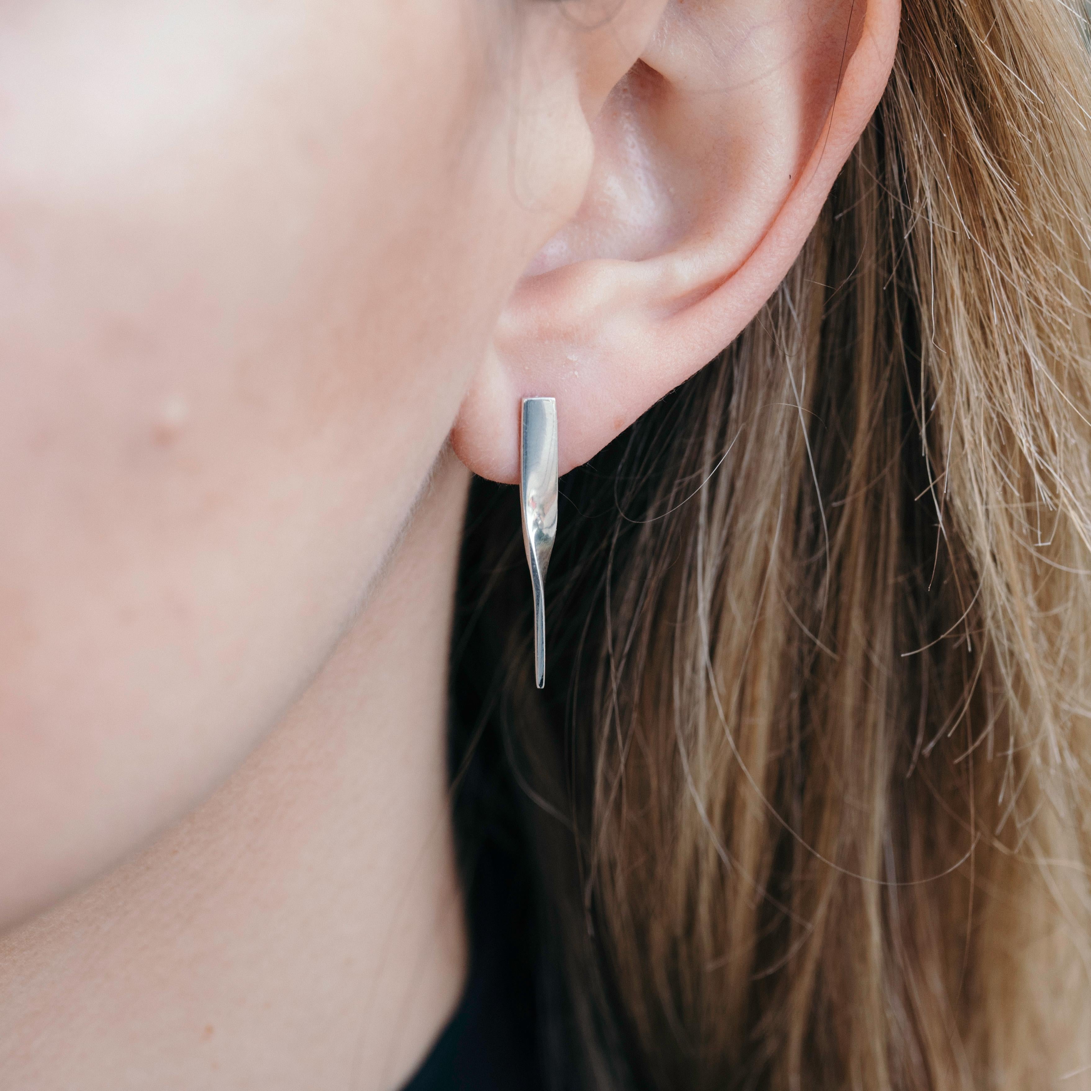 The Shift Earrings taper and twist in unison as they make a graceful quarter turn. The two earrings mirror each other and can be interchanged to reverse their orientation to the face. Their subtle transformation is an ode to shifting perspectives.