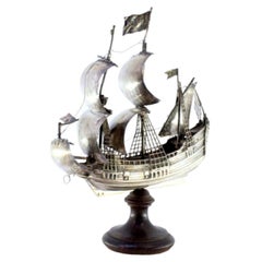 Silver ship with masts and sails, resting on a wooden base