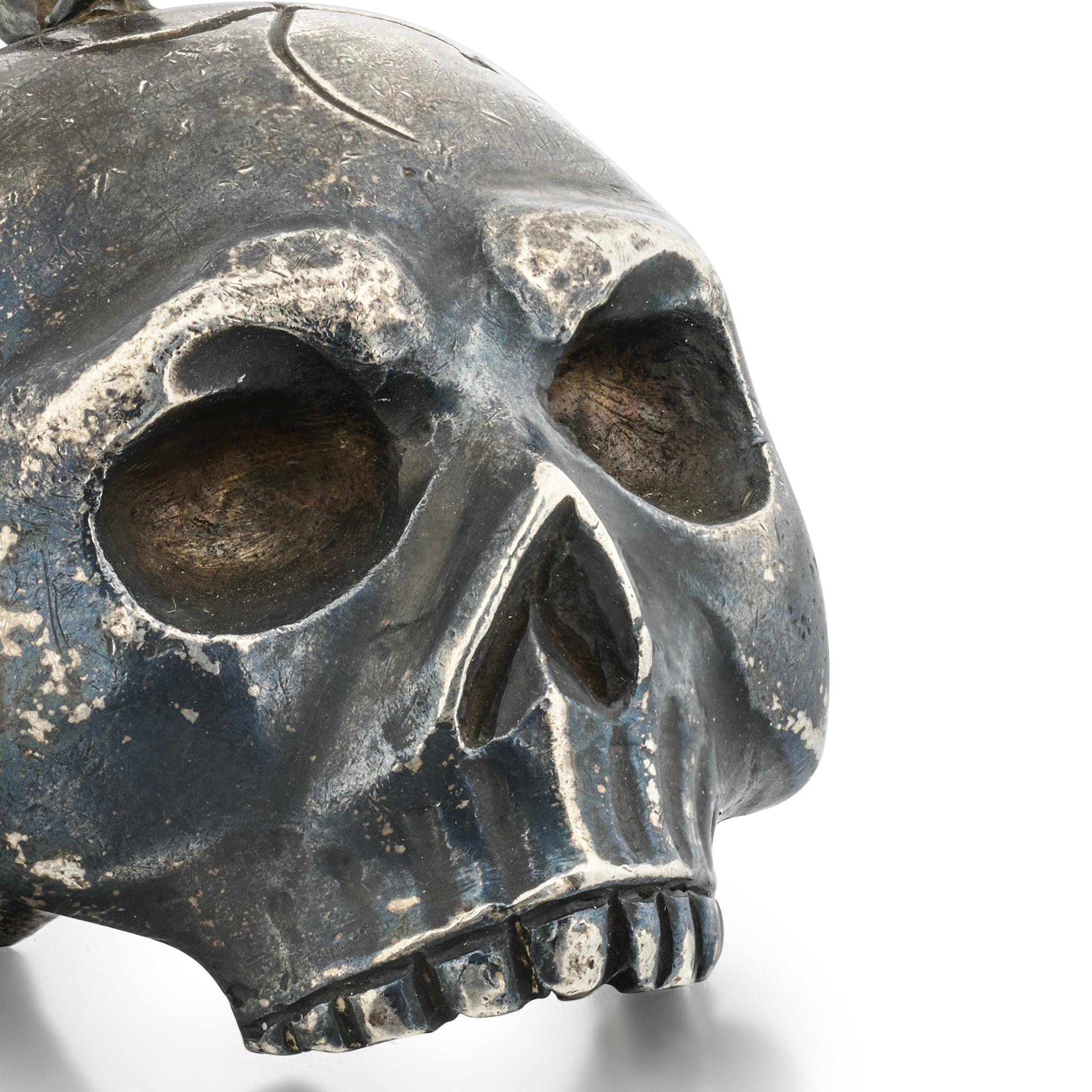 Silver Skull Pendant
 
Probably Italian, 18th–19th century
 
Measurements
5.2 × 4 cm
 
Weight
50 grams
 
Cast in solid silver, this pendant takes the form of a human skull, modelled with pronounced cheekbones, deep-set eye sockets, and a sharply