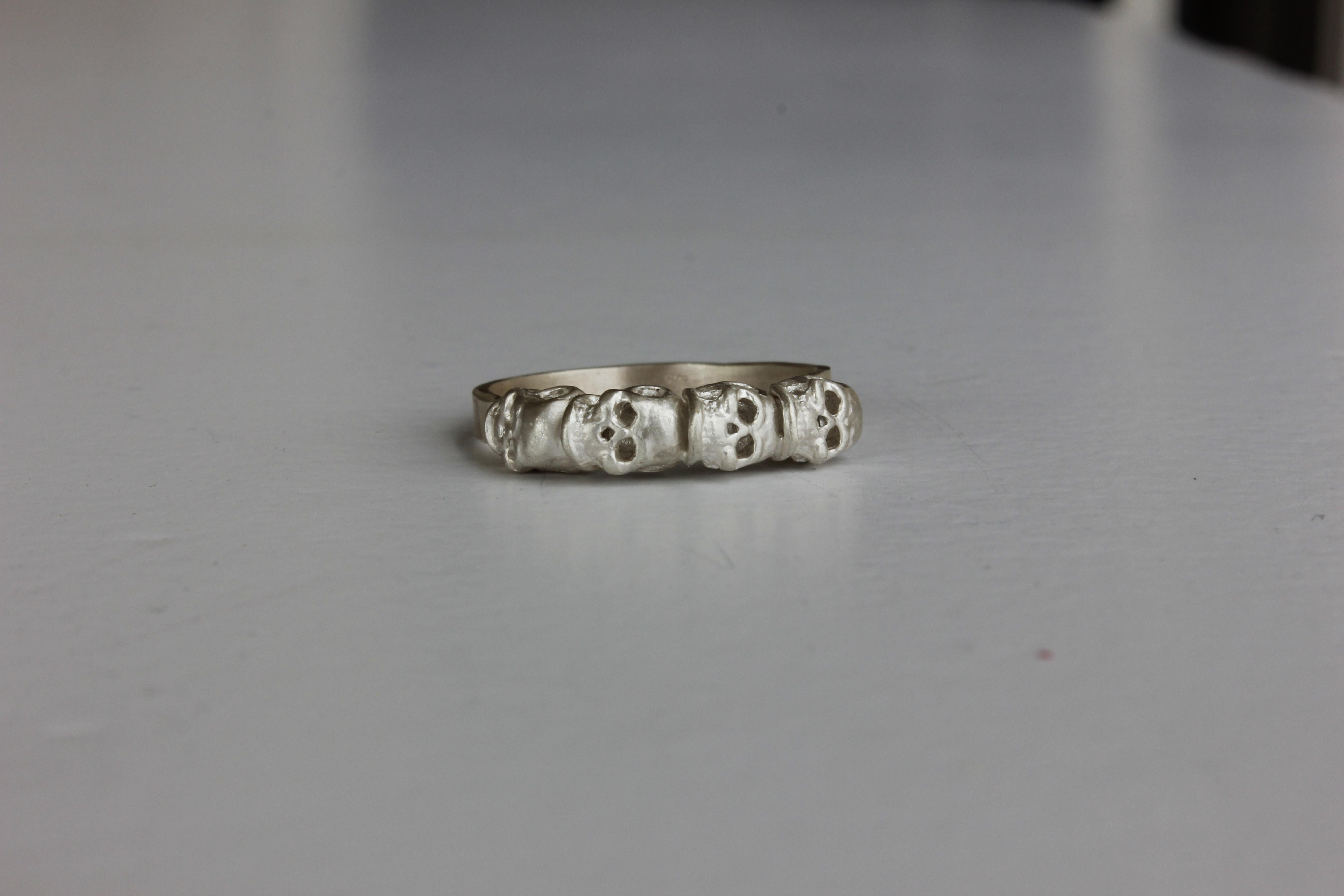 A contemporary silver skull ring featuring a row of four skulls.

This unique, unusual yet beautiful ring can add an elegant detail to your outfit.

