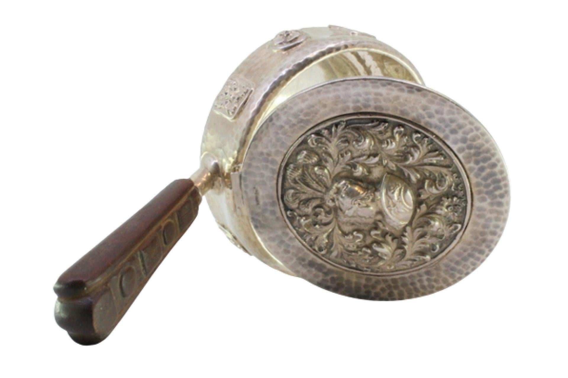 Description: Silver beater with reliefs and bust of Roman soldiers on the hammered lid, reliefs on the surroundings and wooden handle. Metal: Silver. Origin: Portuguese. Mark: standing eagle. Weight: 527.89 grams. Dimensions: 23cmx5cm. Content: