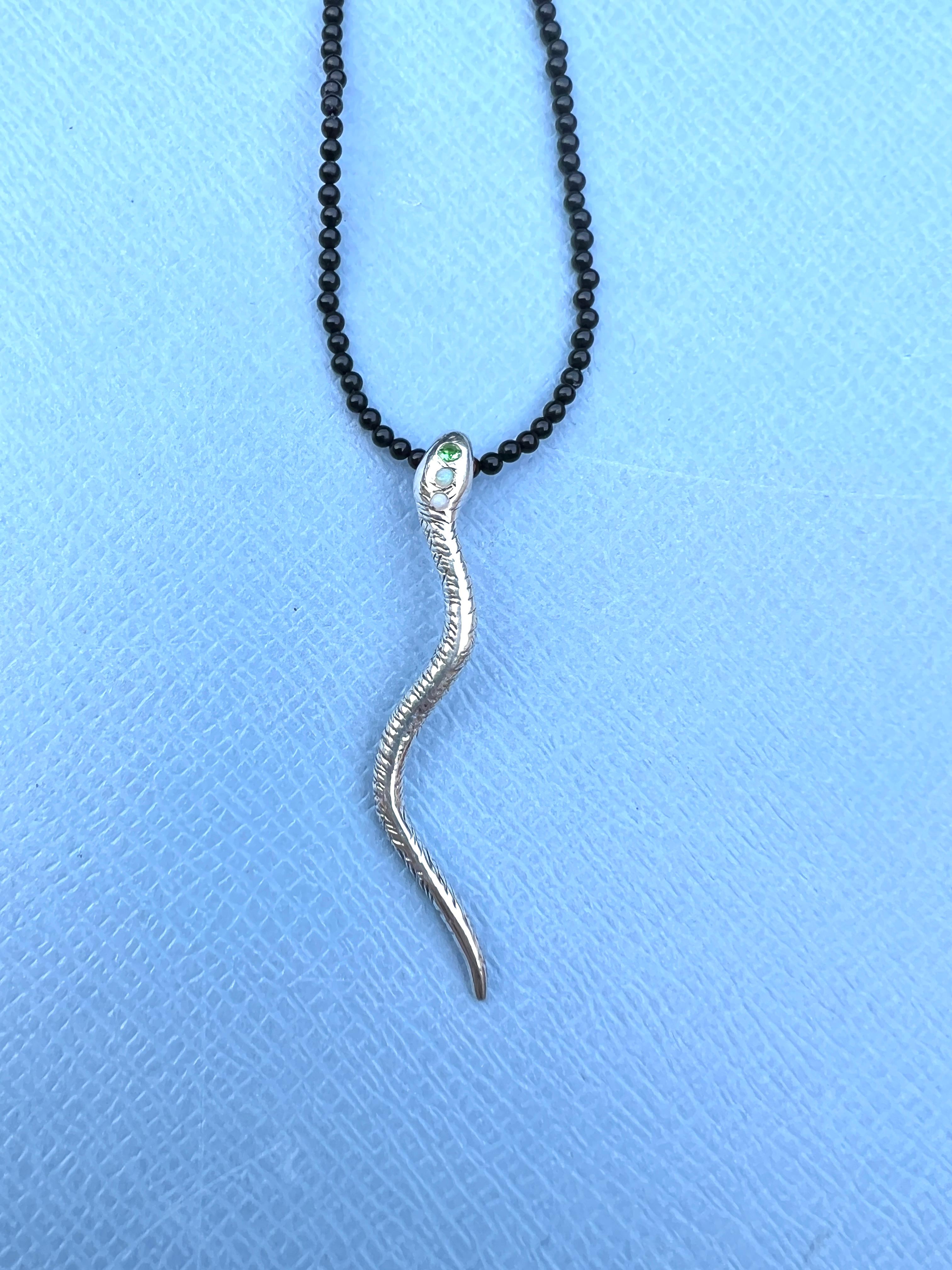 Collana d'argento con ciondolo a forma di serpente Occhi di rubino Perline di onice Granato verde Opale egiziano

Storicamente, serpenti e serpentelli rappresentano la fertilità o una forza vitale creativa. Poiché i serpenti si liberano della loro