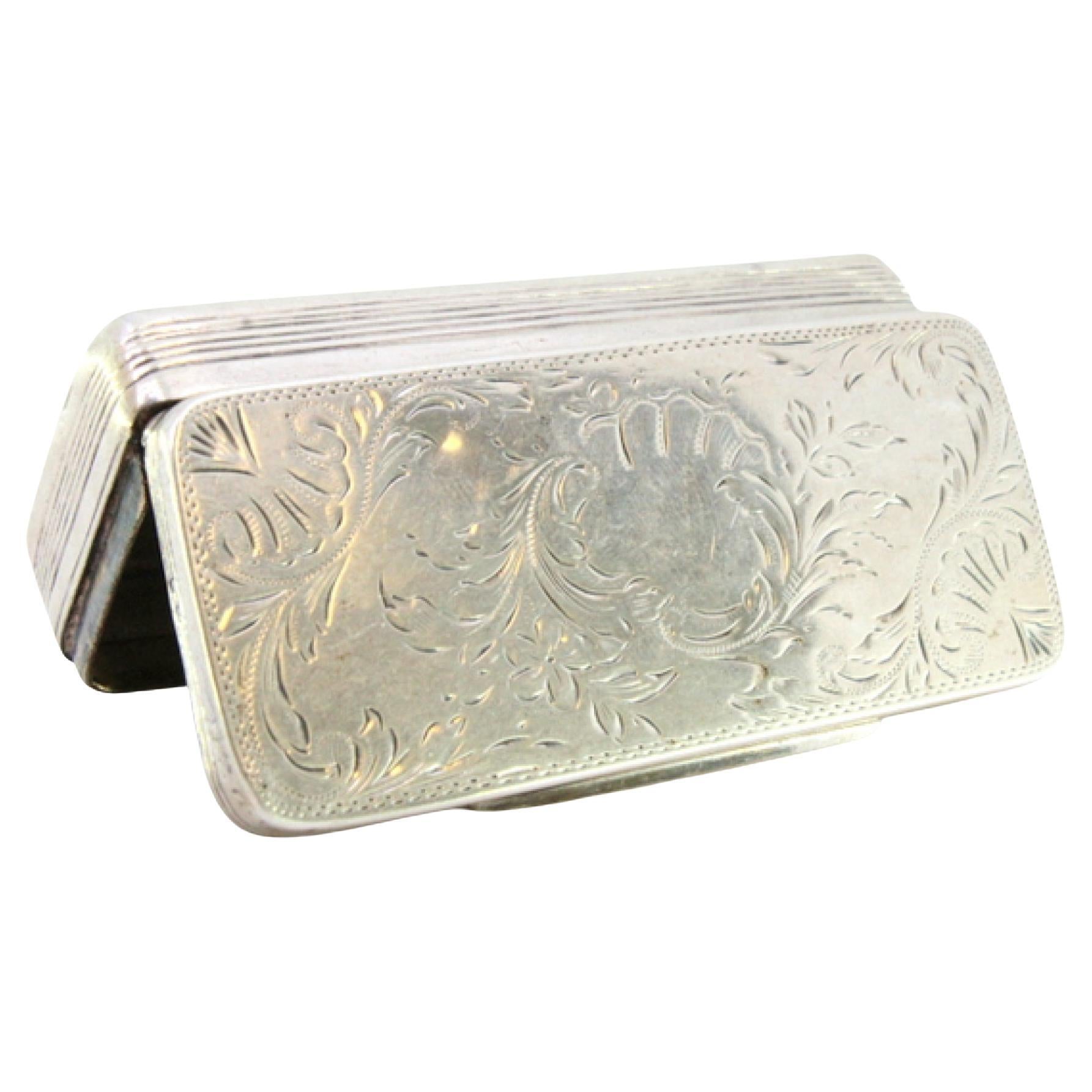 Description: Silver snuff box with engraved wreaths and floral motifs surrounding a monogram card. Metal: Silver. Origin: Portuguese. Brand: Javali II Title. Weight: 85.53 grams. Dimensions: 8.8cmx3.8cm. Content: 833/1000. Assay Mark: Yes, between