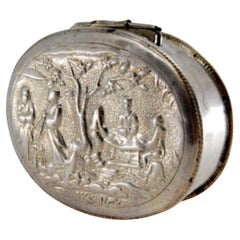Silver snuff box w/ relief everyday motifs in the Oriental style & a hinged lid