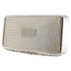 Tabatière en argent avec des bordures sur le bord et un couvercle à charnière gravé.