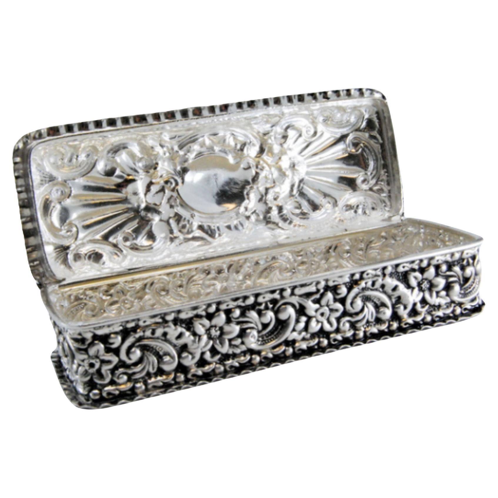 Description: Silver snuff box with embossed designs and hinged lid. Metal: Silver. Origin: English. Brand: Birmingham. Weight: 74.18 grams. Dimensions: 11x2.5cm. Content: 925/1000. Assay Mark: Yes, 1974 by Deakin & Francis. Additional information:
