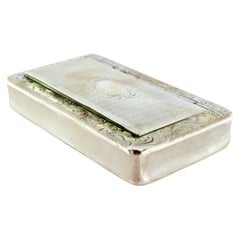 Silver snuff box with engravings surrounding a monogram card on the hinged lid