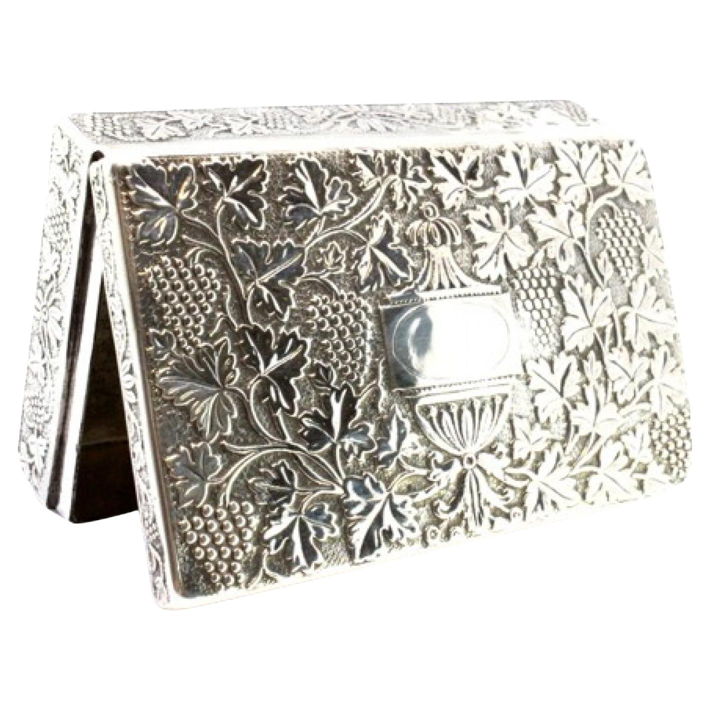 Beschreibung: Silberne Schnupftabakdose mit geprägten floralen Motiven, die eine Monogrammkarte und einen Klappdeckel umgeben. Metall: Silber. Herkunft: Portugiesisch. Marke: Porto Coroa. Gewicht: 206,46 Gramm. Abmessungen: 9,5cmx6cm. Inhalt: