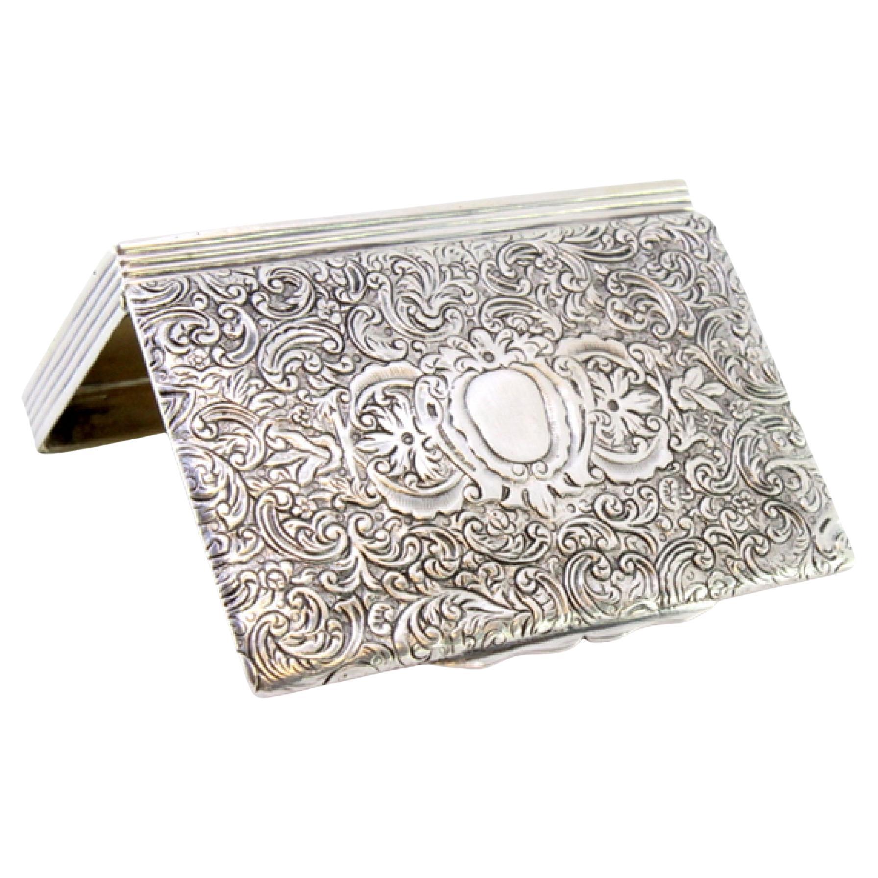 Description : Tabatière en argent avec motifs floraux gravés sur le couvercle et boîtier cannelé avec couvercle à charnière. Métal : Argent. Origine : Portugais. Marque : Fazer. Poids : 122,76 grammes. Dimensions : 8,5 cm x 5,5 cm : 8,5cmx5,5cm.