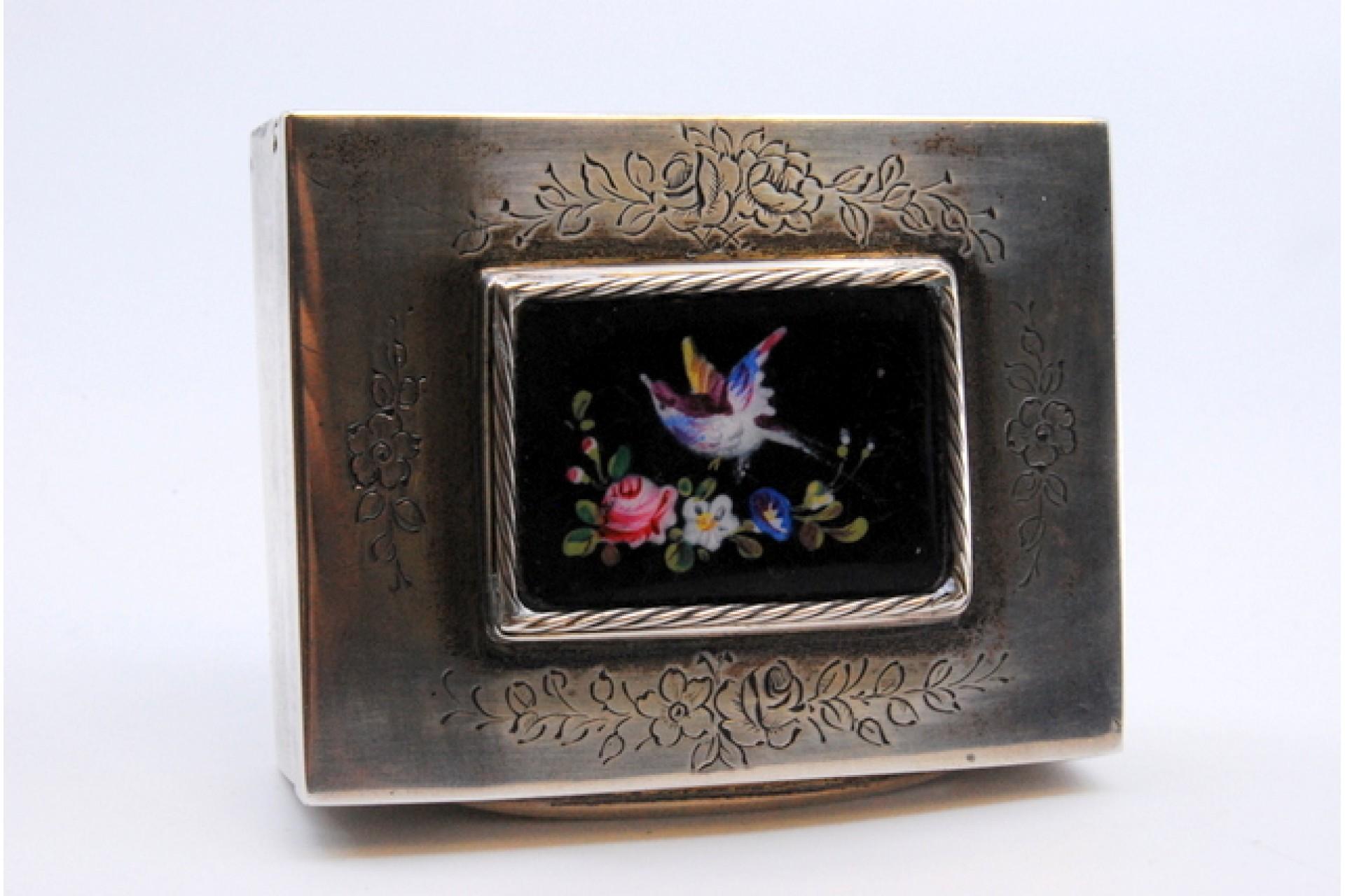 Description: Silver snuff box with engraved floral motifs and enamel with hummingbird on the hinged lid. Metal: Silver. Origin: European. Mark: Absent. Weight: 91.26 grams. Dimensions: 6x4.6cm. Content: 833/1000. Assay Mark: Absent. Additional