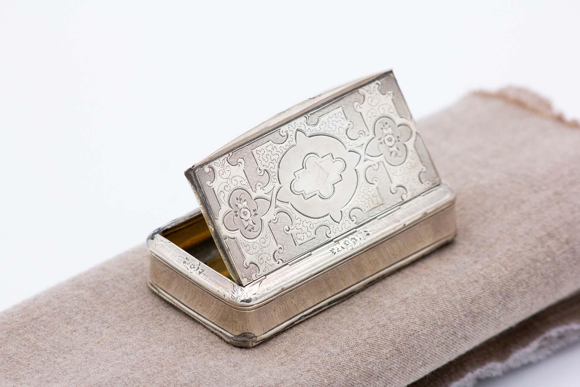 Description: Silver snuff box with gold interior, engraved lid and fluted bottom. Metal: Silver. Origin: French. Brand: Tête Minerve. Weight: 75.24 grams. Dimensions: 8.1cm x 1.8cm. Content: 950/1000. Assay Mark: Yes, since 1838. Additional
