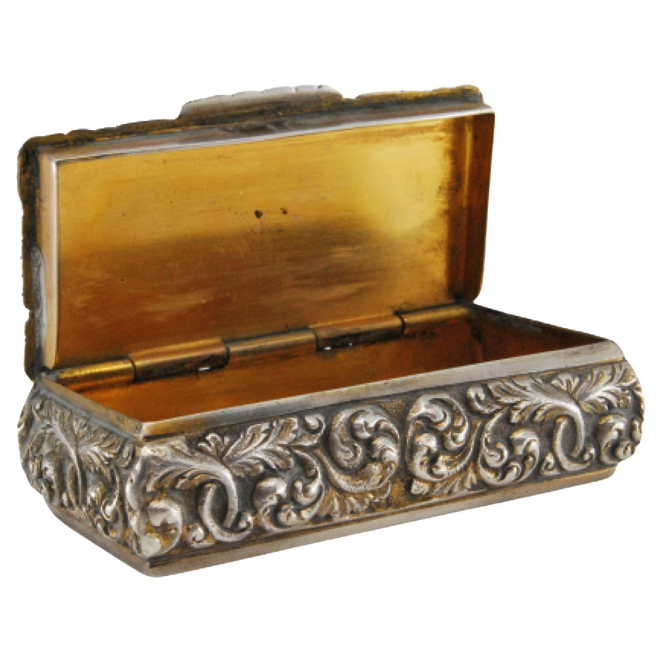 Description: Silver snuff box with reliefs, gold interior and hinged lid. Metal: Silver. Origin: Portuguese. Brand: Cabeça de escravo. Weight: 69.91 grams. Dimensions: 6x1.8cm. Content: 833/1000. Assay Mark: Yes, between 1938 and 1984. Additional