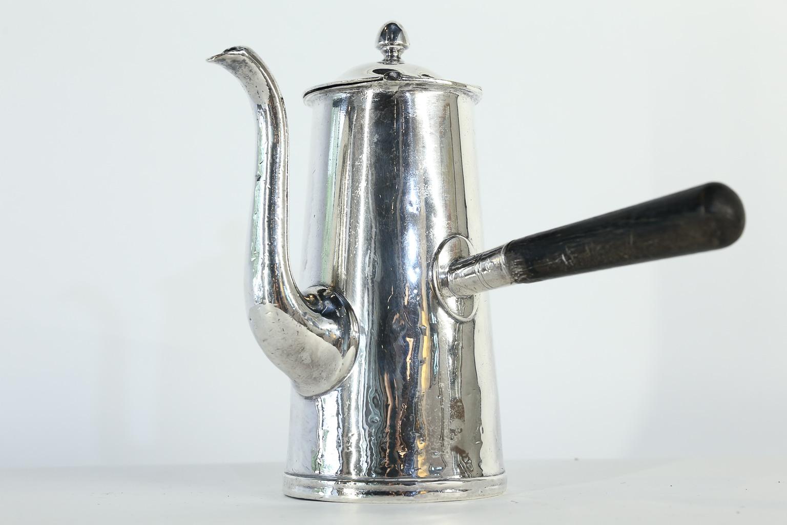 This silver soldered, hotel silver, Reed & Barton coffee or hot chocolate pot was manufactured for the United States Navy. The piece has a hinged top and a wood handle to keep hands cool while serving. Marked on the bottom, REED & BARTON, SILVER