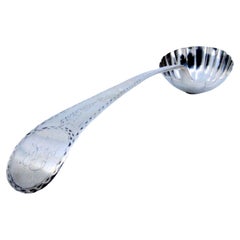 Silver soup ladle in the shape of a shell