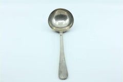 Silver soup ladle in the shape of a shell with grooves along the raised handle