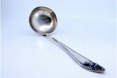 Silver soup ladle w/ a raised strip along the handle surrounding a monogram card
