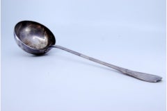 Silver soup ladle w/ friezes & palms on the handle surrounding a monogram card