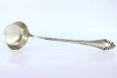 Silver soup ladle w/ friezes & reliefs on the handle surrounding a monogram card