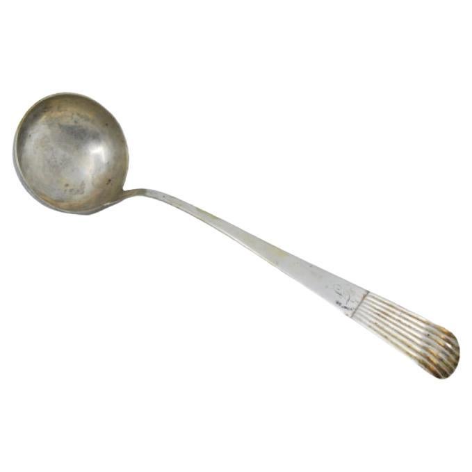 Silver soup ladle with a strip along the handle