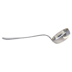 Silver soup ladle with aligned grooves on the handle and reliefs on both sides