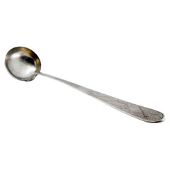 Silver soup ladle with engravings along the handle, including a monogram card