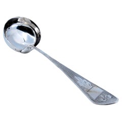 Silver soup ladle with engravings along the handle, including a monogram card
