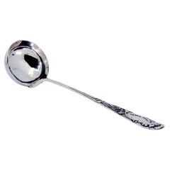 Silver soup ladle with floral relief handle and monogram cartouche