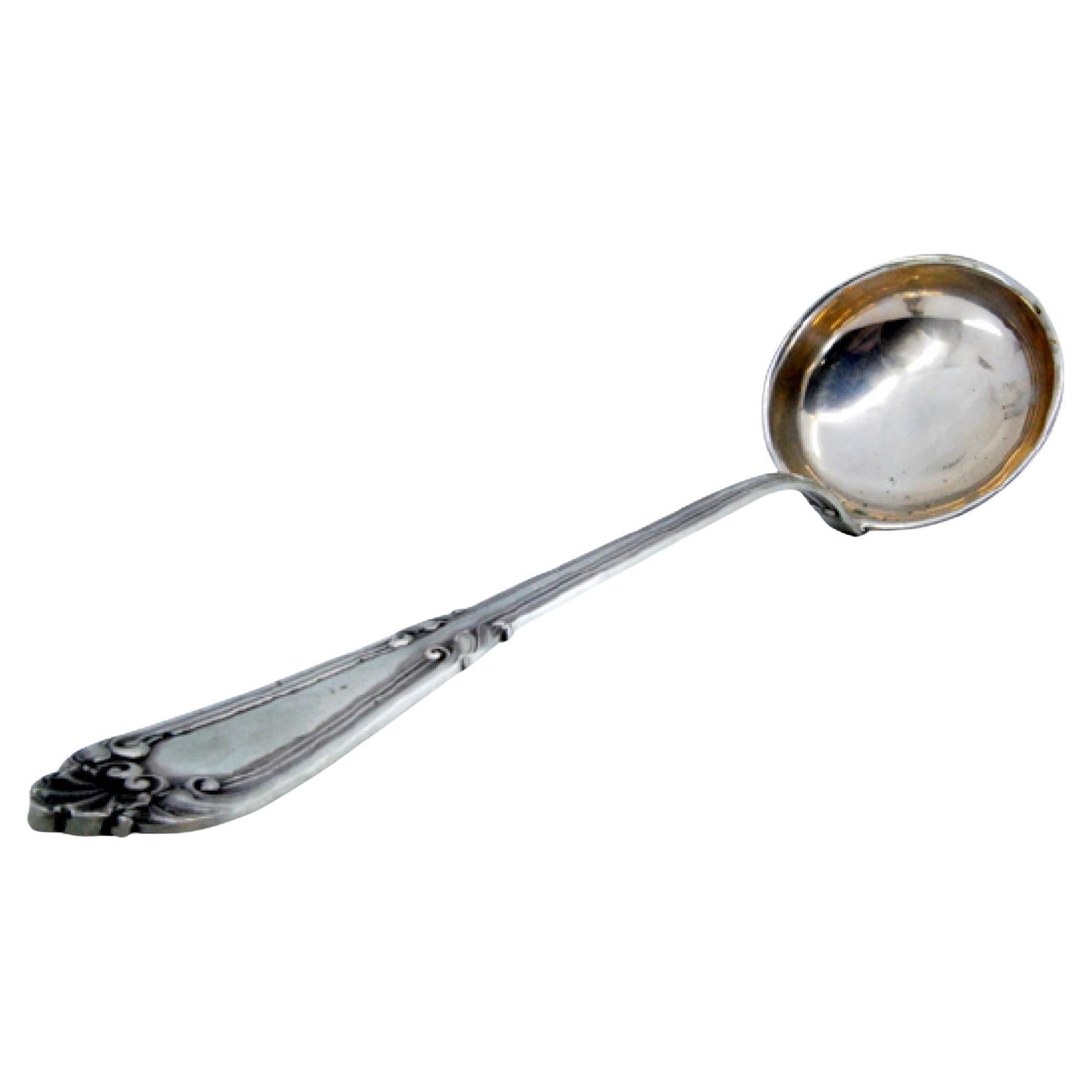 Silver soup ladle with grooved handle and relief monogram cartouche