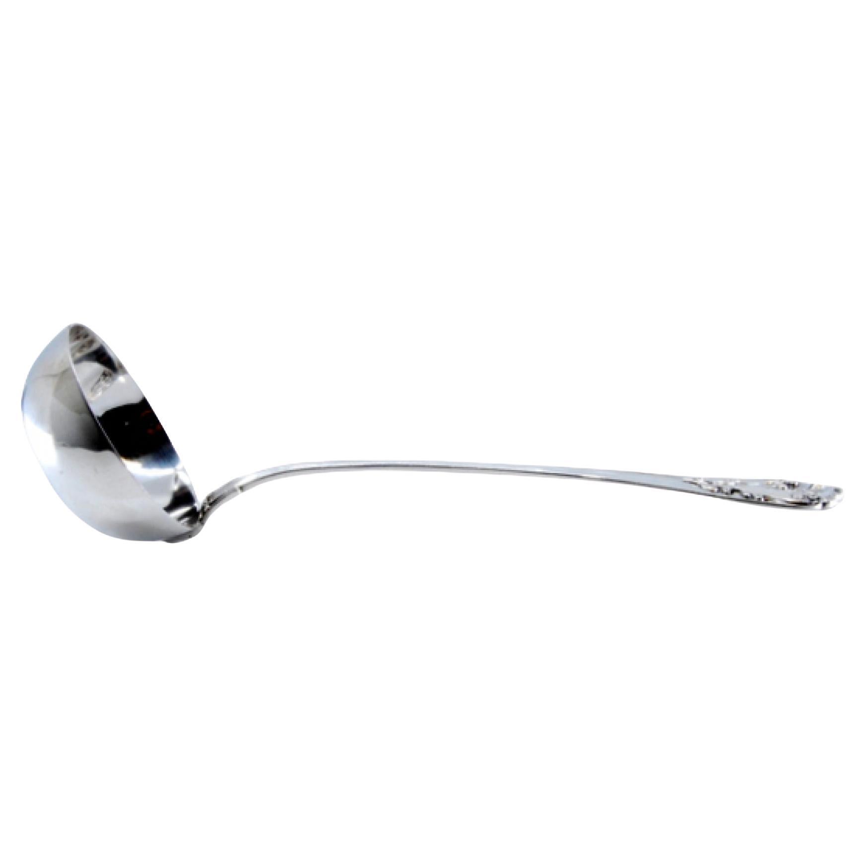 Silver soup ladle with grooved handle and relief monogram cartouche