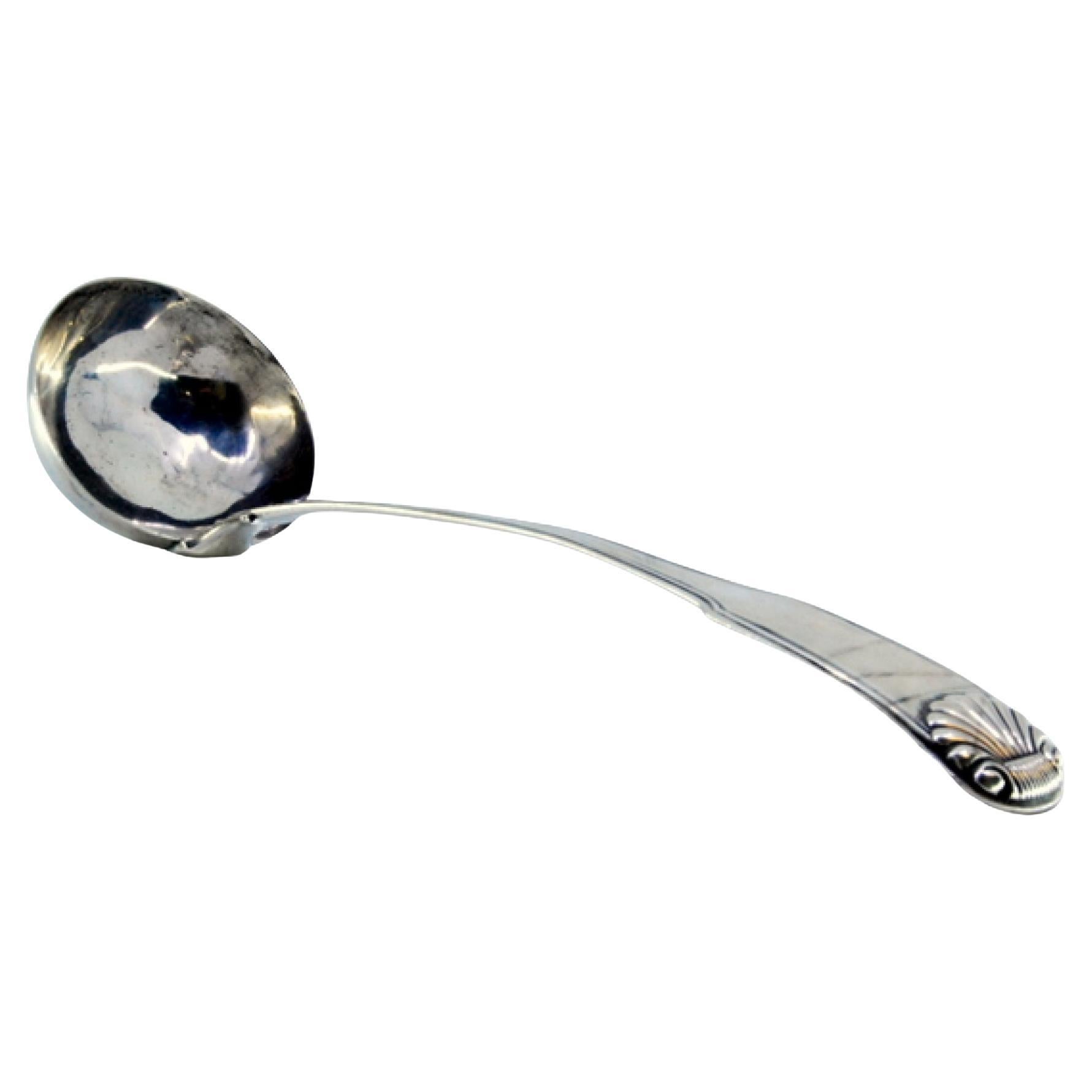 Silver soup ladle with grooves along the handle and embossed shell