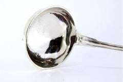 Silver soup ladle with grooves along the handle and monogram plaque