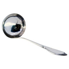 Silver soup ladle with grooves along the handle and monogram plaque