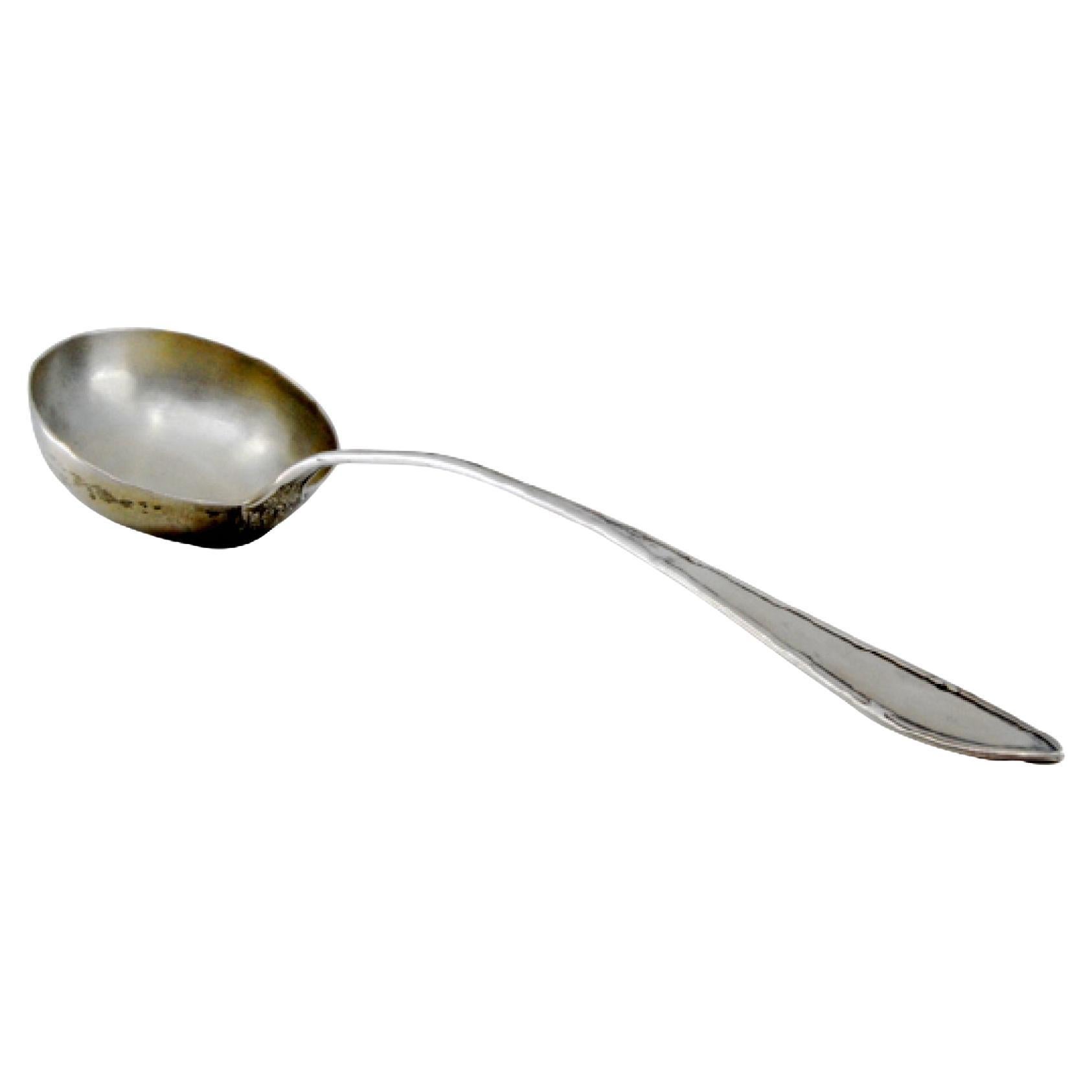 Silver soup ladle with grooves along the handle