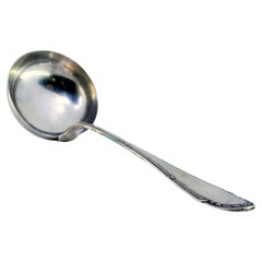Silver soup ladle with grooves along the handle