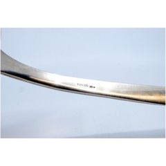 Silver soup ladle with grooves along the handle surrounding a monogram card