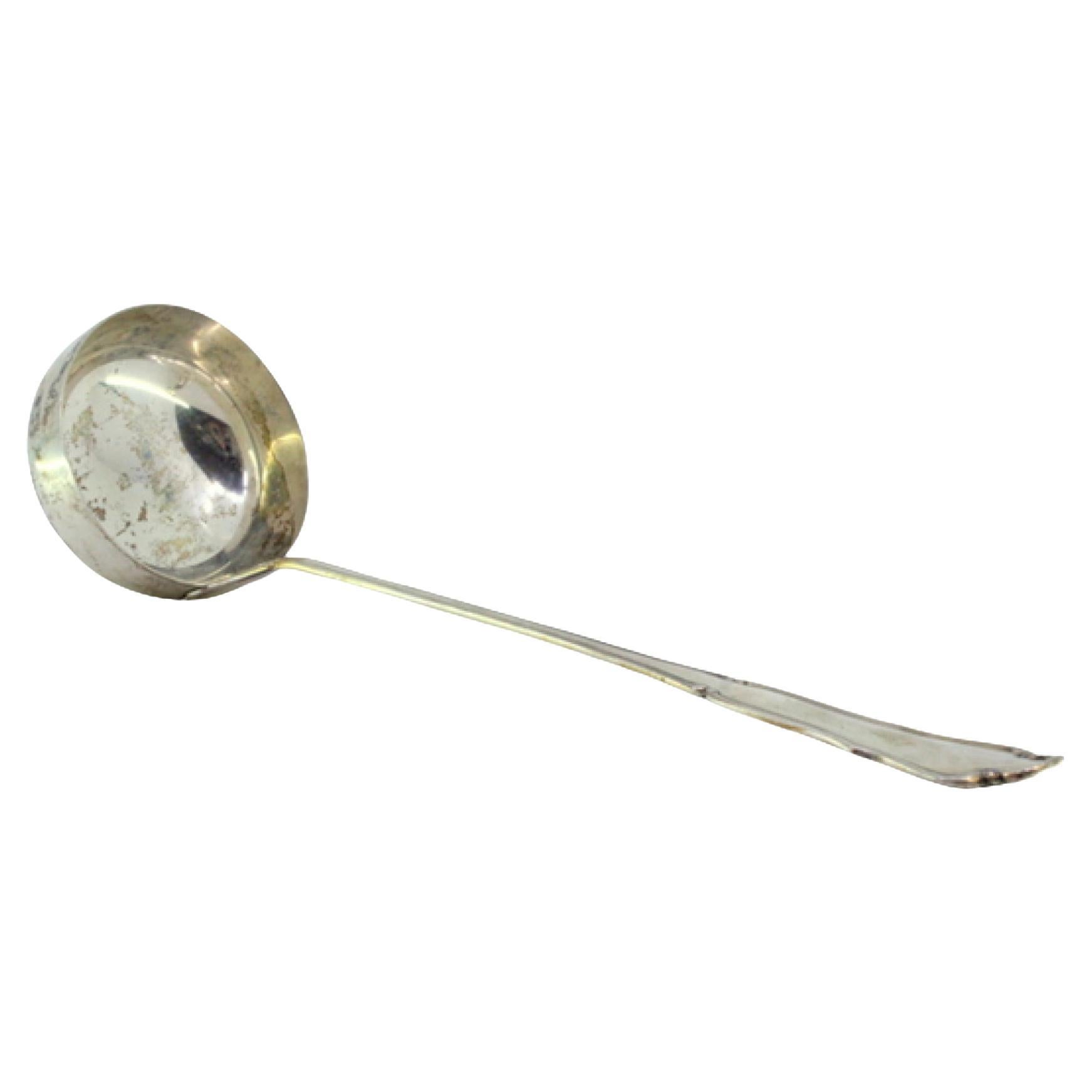 Silver soup ladle with grooves along the scalloped handle