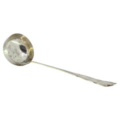 Silver soup ladle with grooves along the scalloped handle