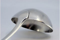 Silver soup ladle with grooves on the handle surrounding a monogram card