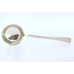 Silver soup ladle with reliefs along the handle