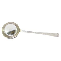 Silver soup ladle with reliefs along the handle