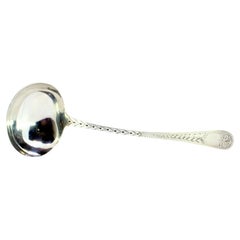 Silver soup ladle with reliefs along the handle surrounding a monogram card