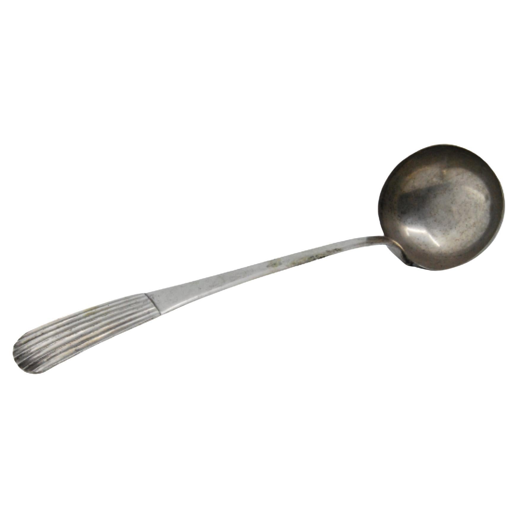 Silver soup ladle with reliefs along the reed-style handle
