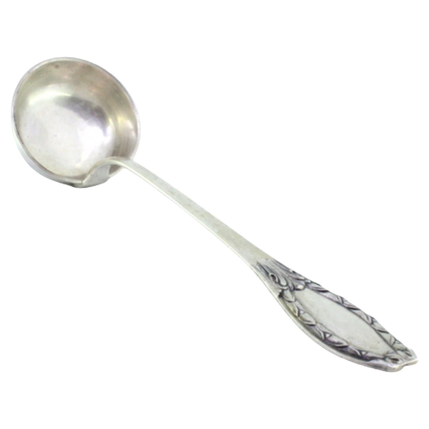 Silver soup ladle with reliefs on the handle surrounding a monogram card