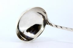 Silver soup ladle with wavy handle and engravings surrounding a monogram card