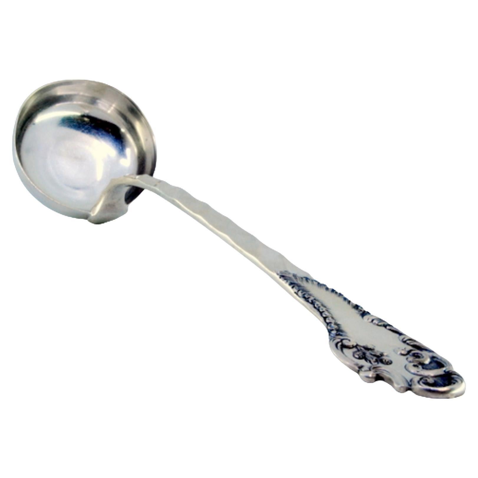 Silver soup ladle with wavy reliefs on the handle, surrounding a monogram card