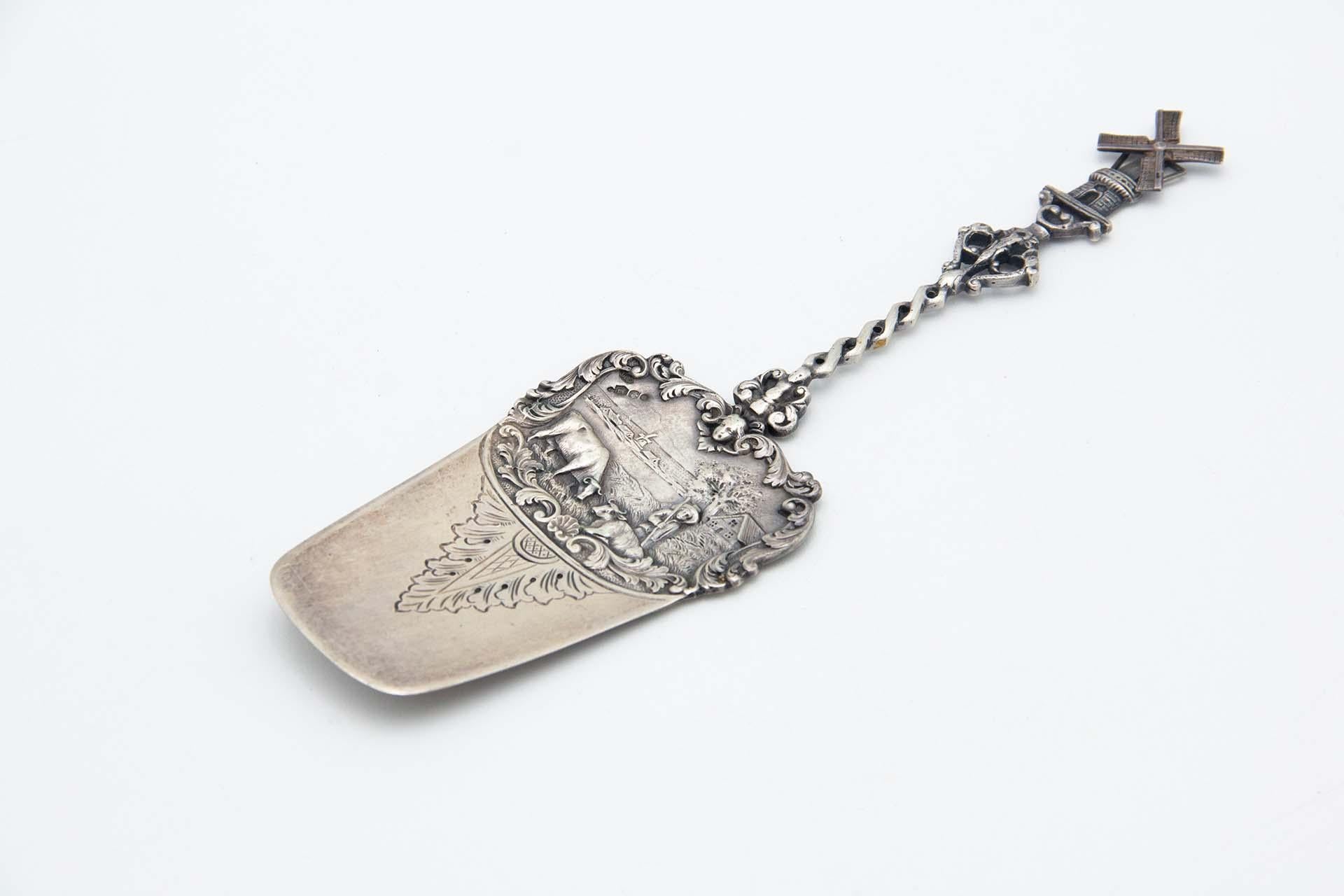 Description: Silver spatula with reliefs of a bucolic scene, twisted handle and articulated mill in perfect shape. Metal: Silver. Origin: Dutch. Mark: Head of Minerva with helmet. Weight: 81.95 grams. Dimensions: 24cm x 0.5cm. Content: 833/1000.